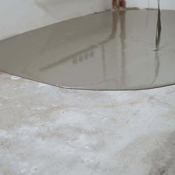 Construction worker pouring self-leveling concrete mix on the floor