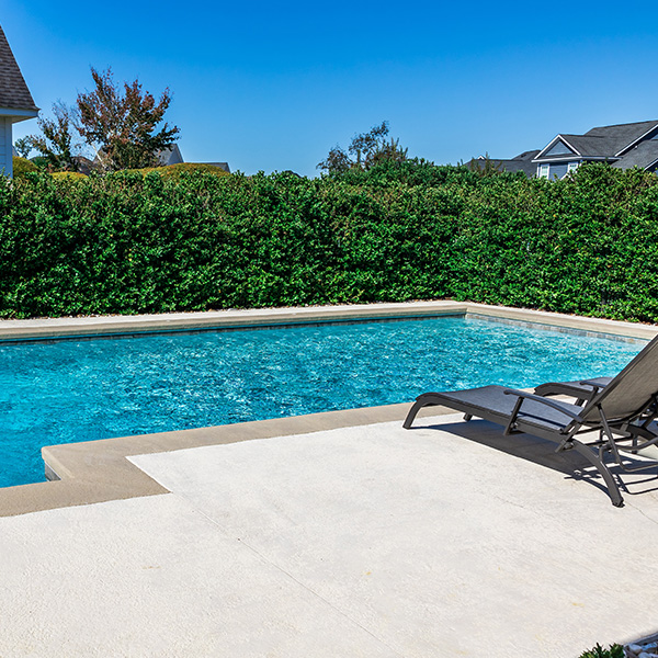 Rectangular new swimming pool with tan concrete edges
